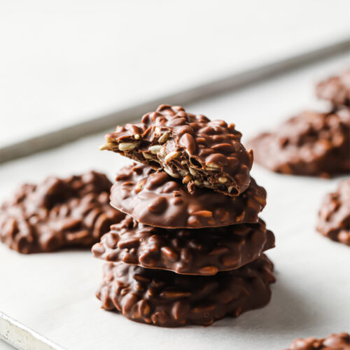 Side/close-up shot of the Chocolate Sunflower Seed Clusters stacked and lined in a baking sheet with parchment paper.
