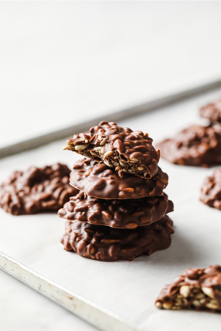 Side/close-up shot of the Chocolate Sunflower Seed Clusters stacked and lined in a baking sheet with parchment paper.