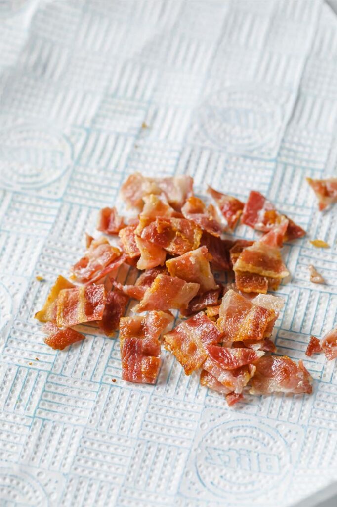 Overhead shot of crumbled bacon in a towel-lined plated.
