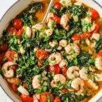 Overhead shot of the One-Pan Low-Carb Tuscan Garlic Shrimp, garnished with chopped fresh parsley and Italian seasoning, served in a cooking pot with a serving spoon.