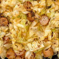 overhead shot of chicken sausage and cabbage skillet in cast-iron skillet atop marble countertop