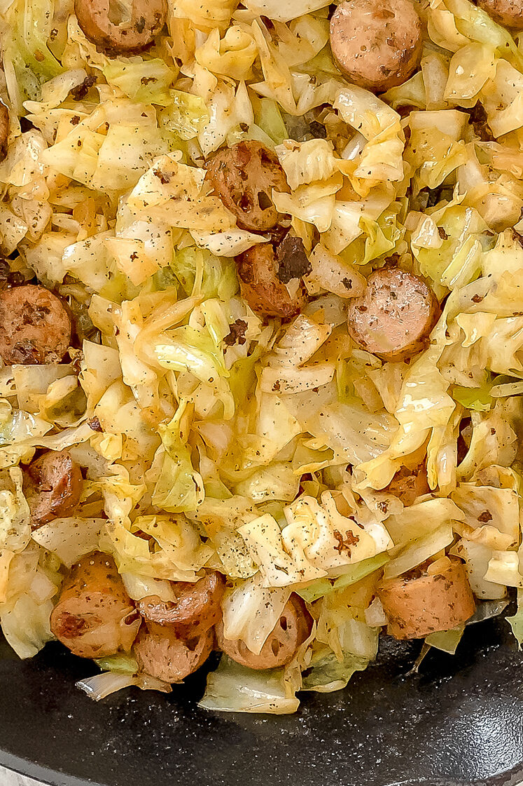 overhead shot of chicken sausage and cabbage skillet in cast-iron skillet atop marble countertop