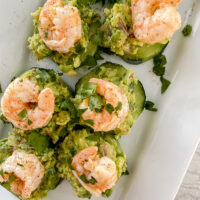overhead shot of cucumber bites with shrimp on top of white serving plate