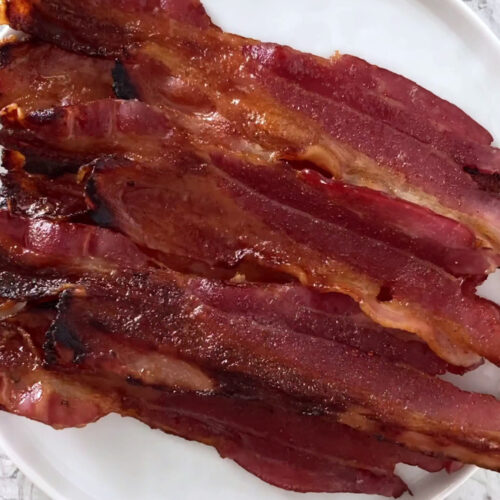 Overhead shot of a plate with keto spicy candied bacon atop a marble countertop.