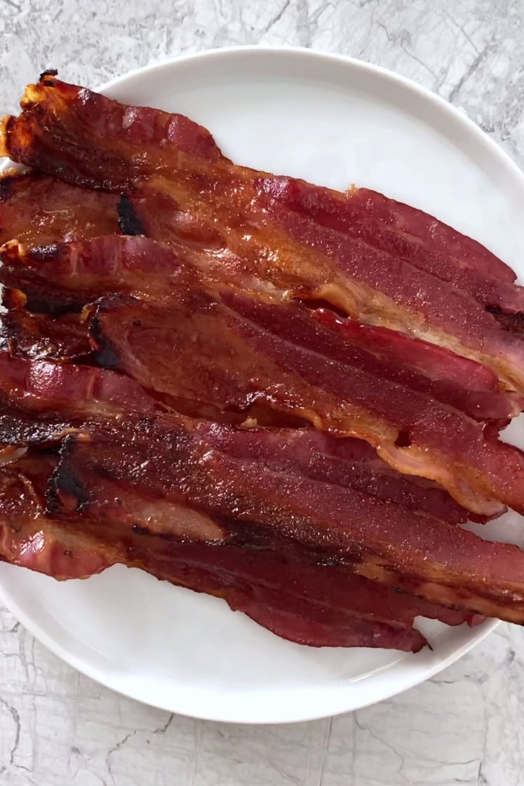 Overhead shot of a plate with keto spicy candied bacon atop a marble countertop.