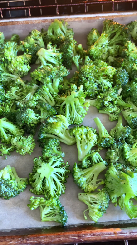 Overhead shot of broccoli florets in a baking pan lined with parchment paper.