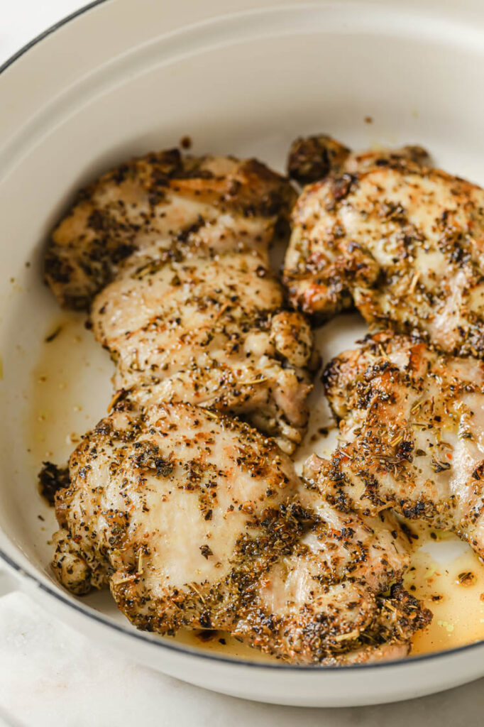 Overhead shot of a large pan with the seasoned chicken cooked in oil until golden brown.