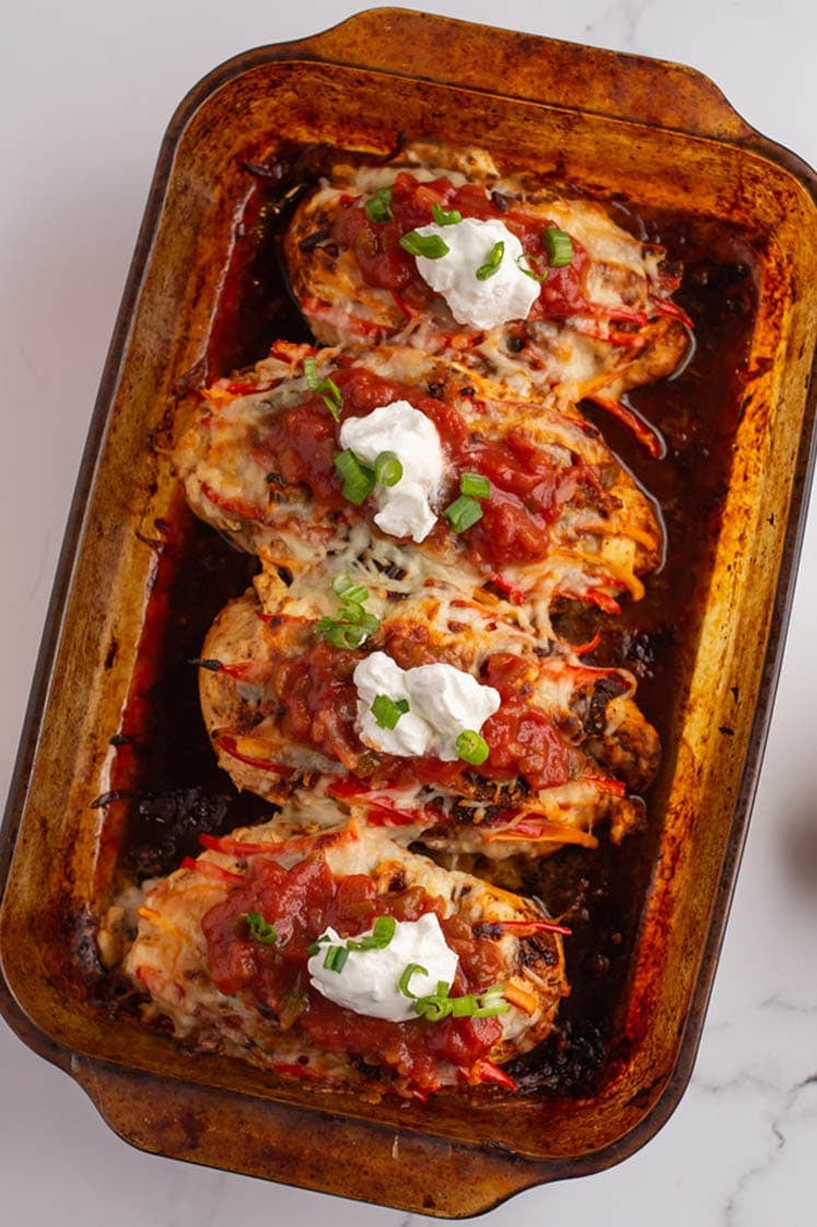 overhead shot of garnished chicken bake casserole dish sitting diagonally atop marble countertop