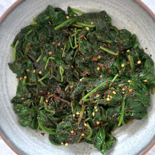 Garnished lemon garlic spinach on a plate.