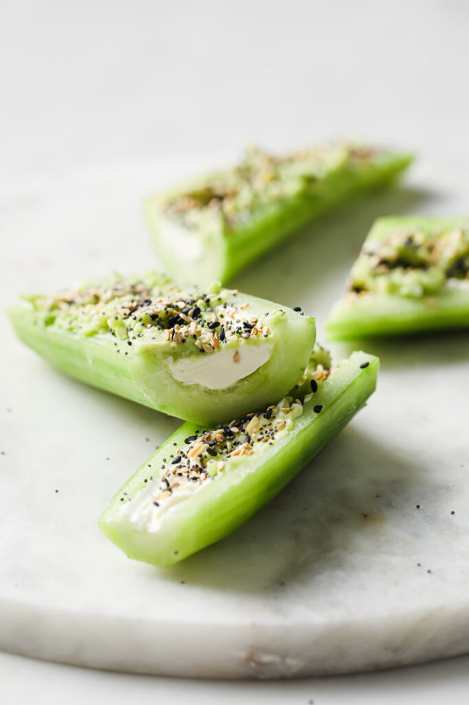 Angled close-up shot of sliced Everything Bagel Seasoning Cucumber Boats atop a marble plate. The plate rests atop a marble countertop.