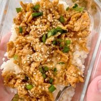 overhead shot of hands holding meal prep container of firecracker ground chicken with cauliflower rice in meal prep container with fork