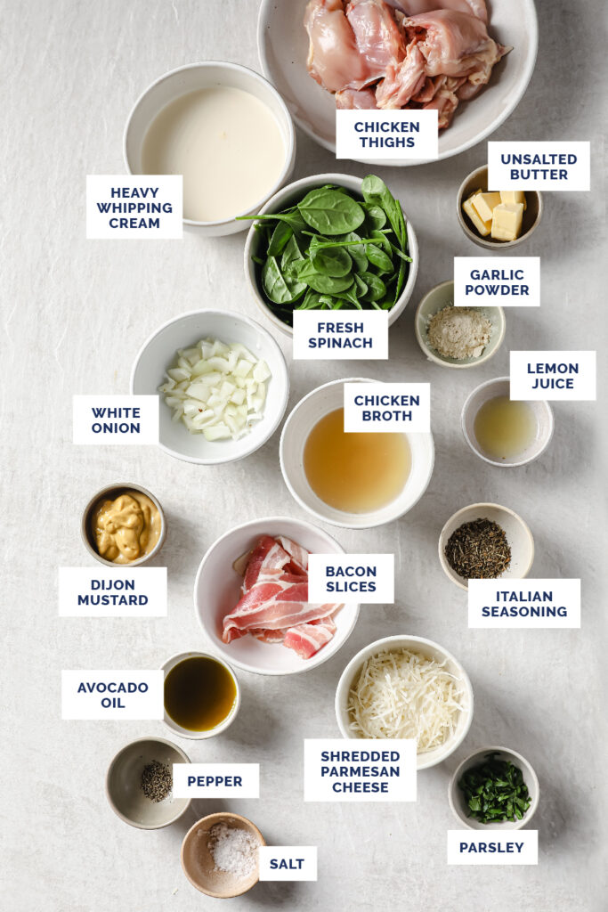 Overhead shot of labeled ingredients for the One-Pan Creamy Dijon Chicken in bowls atop a marble countertop.