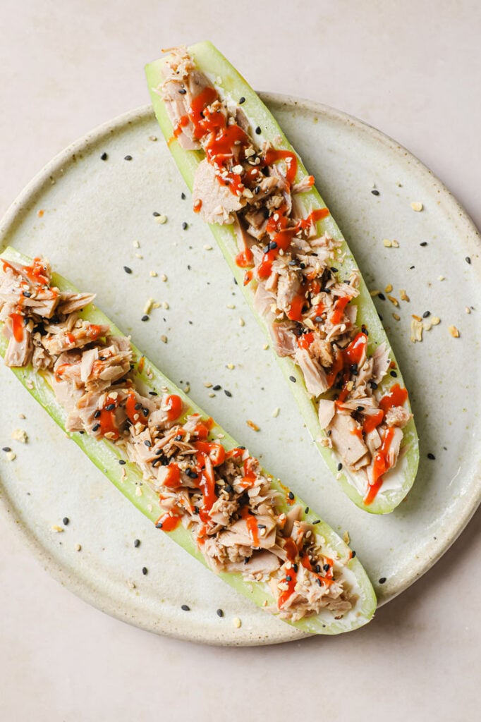 Overhead shot of the spicy keto tuna cucumber boats with cream cheese on a ceramic plate atop a marble countertop.