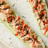 Overhead close-up shot of the spicy keto tuna cucumber boats with cream cheese on a ceramic plate atop a marble countertop.