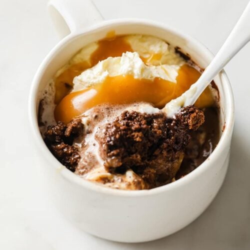 Low-Carb Double Chocolate Mug Cake with ice cream and caramel and a spoon.