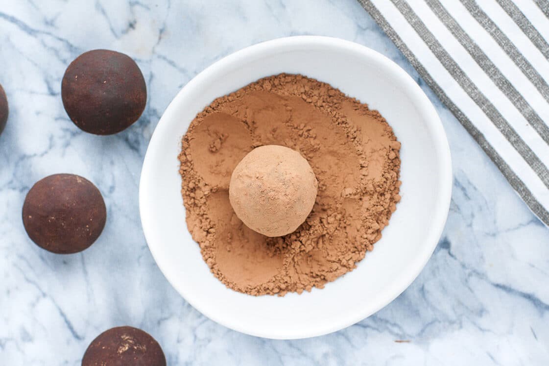 Chocolate truffles dusted with cocoa powder on a marble surface.