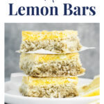 Keto Lemon Bars WordPress Pin. Above the photo, there’s an avocado green text box with white letters that say: “gluten-free · nut-free · dairy-free”. Below the avocado-green text box, there’s text in navy blue letters that say: “Keto Lemon Bars”. The photo shows a side close-up of three Keto Lemon Bars stacked and separated by parchment papers, with lemon slices on a ceramic plate. There’s also one lemon slice beside the plate. The plate and the lemon slice rest atop a marble countertop. Below the photo, there’s text in navy blue letters that say: “realbalanced.com”.