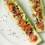 Chive And Onion Cucumber Boats on a ceramic plate atop a marble countertop.