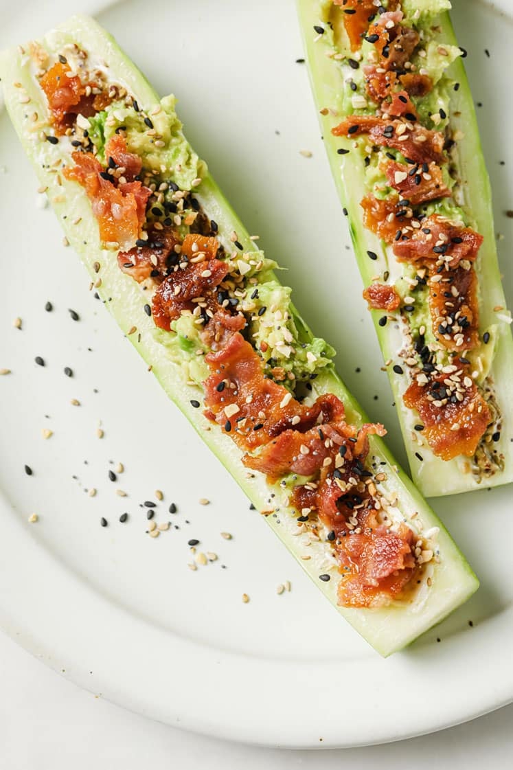 Chive And Onion Cucumber Boats on a ceramic plate atop a marble countertop.