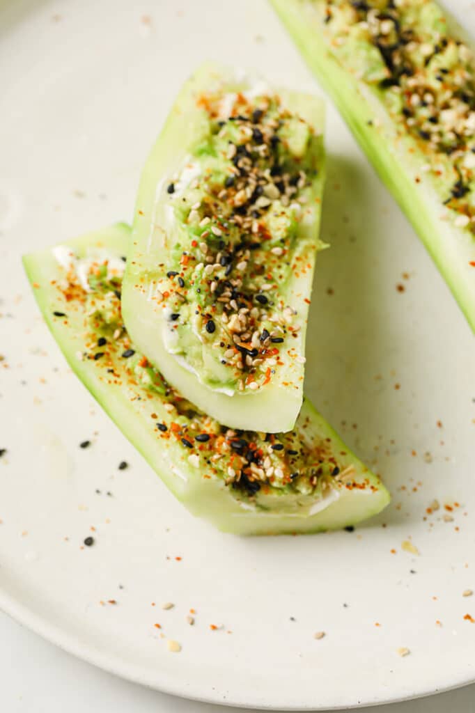Sliced Tajin Cucumber Boats with Lime Juice on a ceramic plate atop a marble countertop.