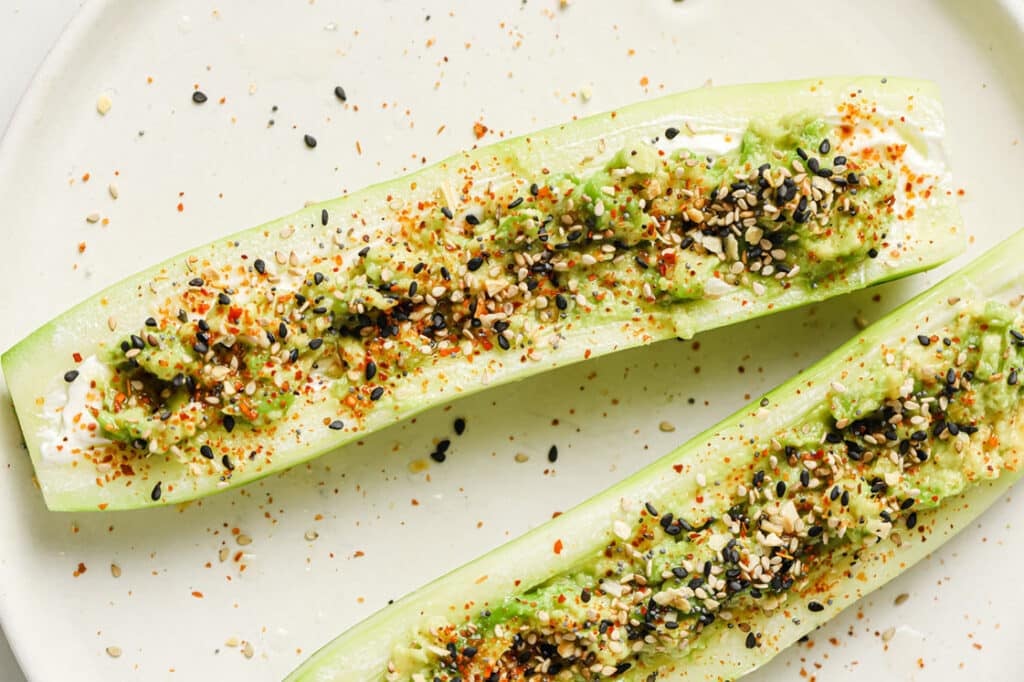 Tajin Cucumber Boats with Lime Juice on a ceramic plate atop a marble countertop.