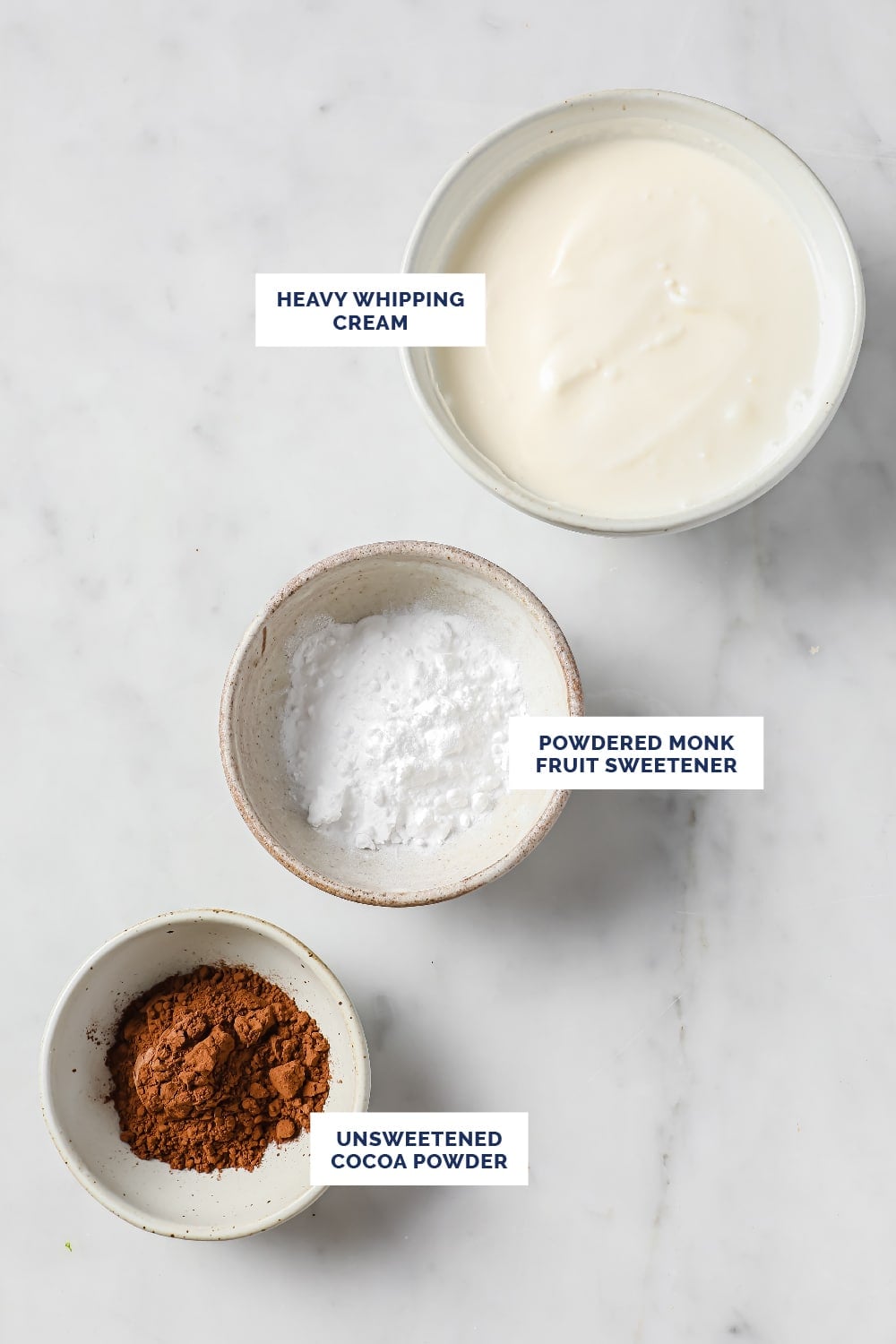 Labeled ingredients for the Keto Frosty recipe in bowls atop a marble countertop.