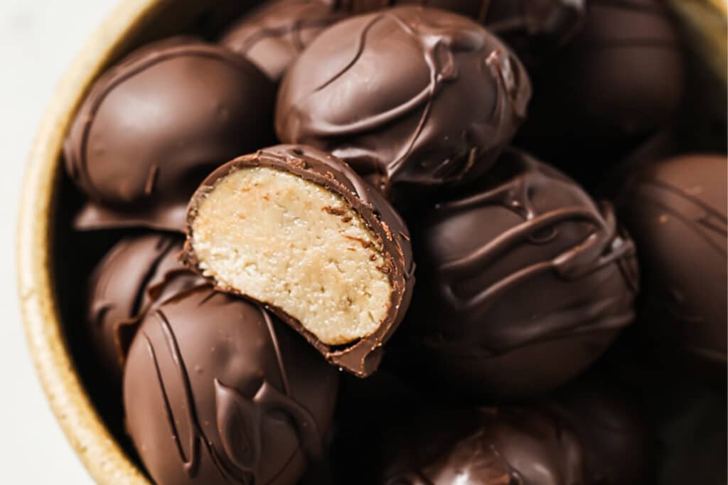 Chocolate Peanut Butter Balls with one halved ball in a bowl.