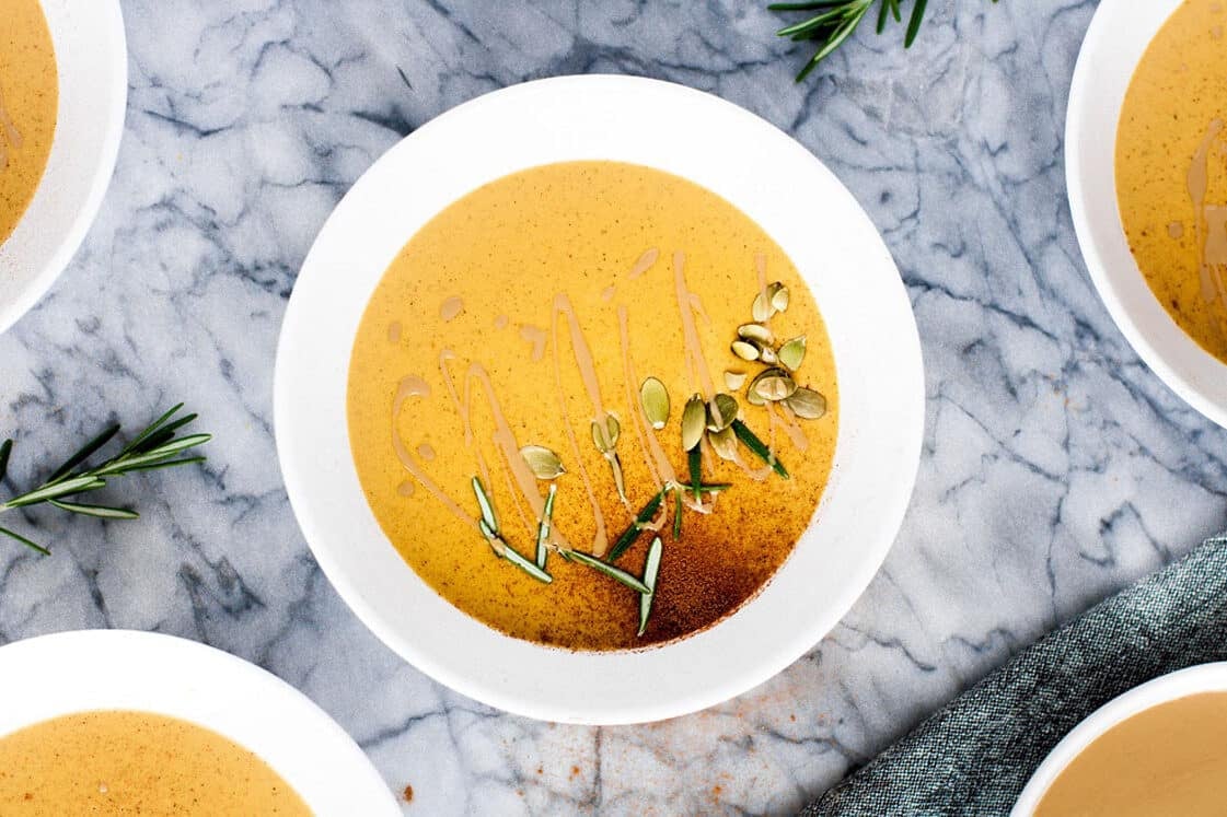 Bowls of pumpkin soup with sprigs of rosemary.