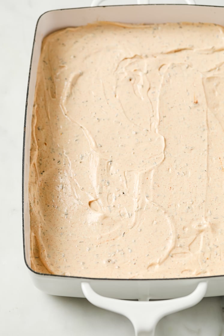A rectangular white baking dish filled with a smooth, creamy, speckled mixture spread evenly across the surface, ready to be baked or chilled.