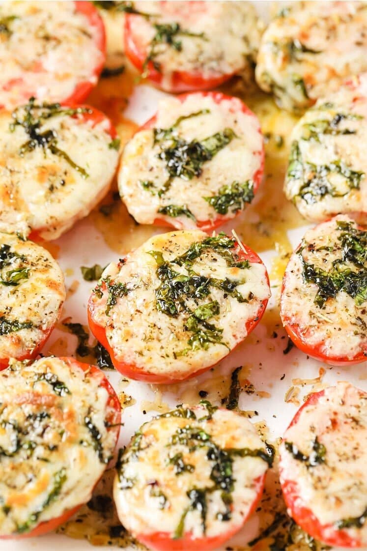 Baked Tomatoes With Parmesan And Mozzarella Cheese on a parchment paper-lined baking pan.
