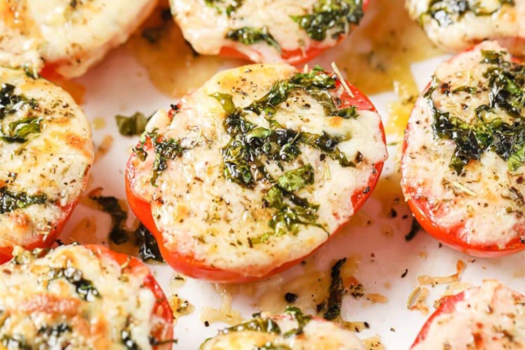 Baked Tomatoes With Parmesan And Mozzarella Cheese on a parchment paper-lined baking pan.