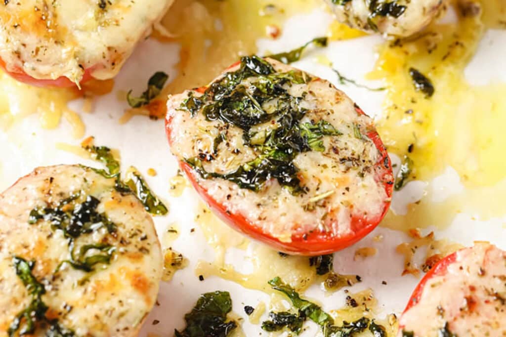 Baked Tomatoes With Parmesan And Mozzarella Cheese on a parchment paper-lined baking pan.