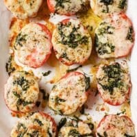 Baked Tomatoes With Parmesan And Mozzarella Cheese on a parchment paper-lined baking pan.