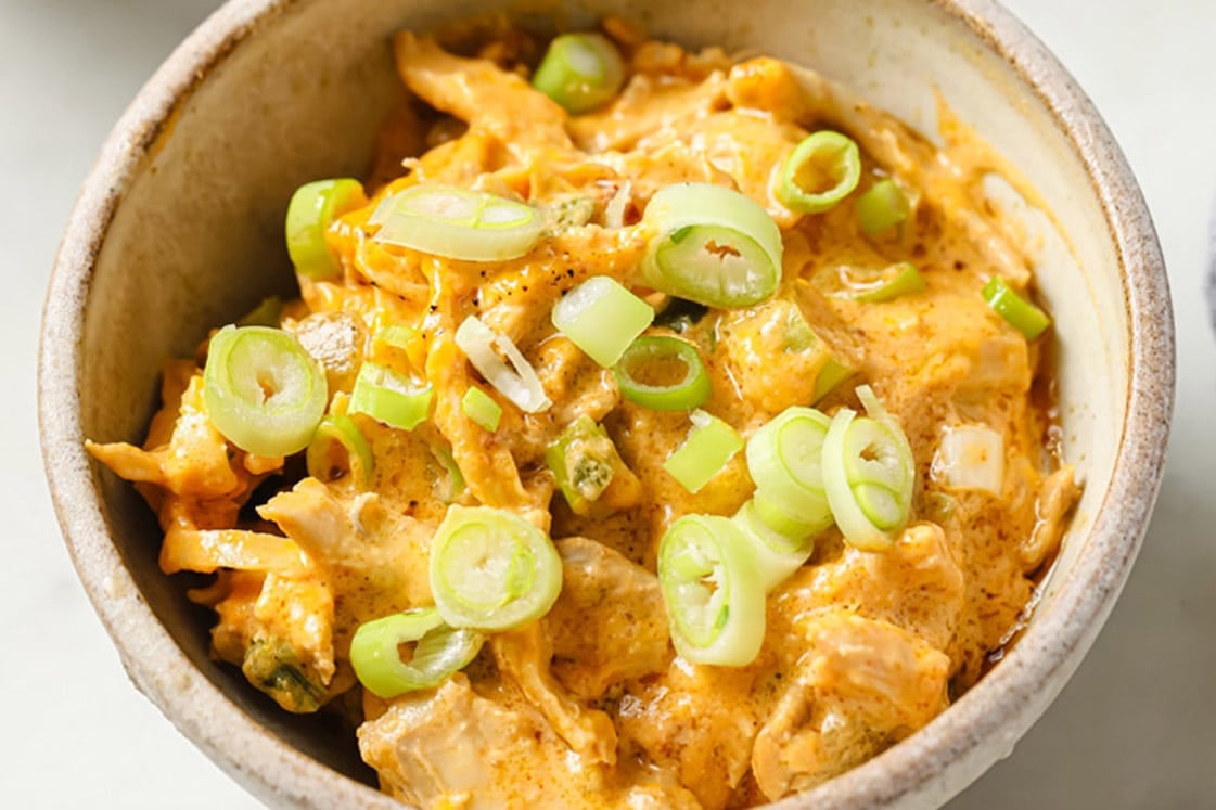 Green Chile Chicken With Leftover Shredded Chicken Thighs in a small bowl atop a marble counter.