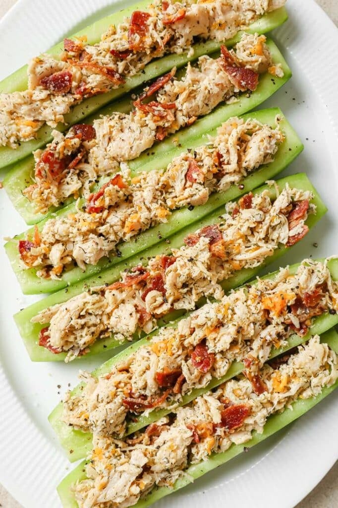 Bacon ranch chicken salad cucumber boats on a plate atop a marble countertop.
