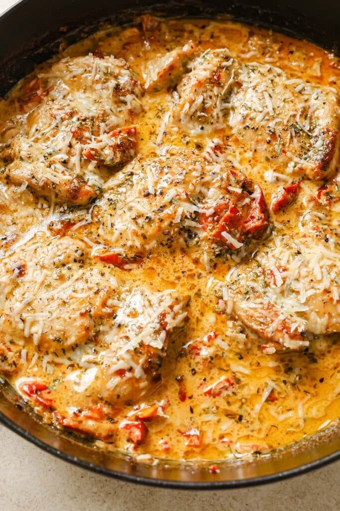 Sun dried tomato chicken topped with shredded cheese in a skillet.