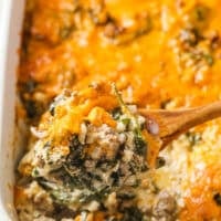 Cheesy beef casserole with cauliflower rice and spinach in a white ceramic baking dish.