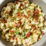 Garnished fried cabbage with bacon dish in a skillet.