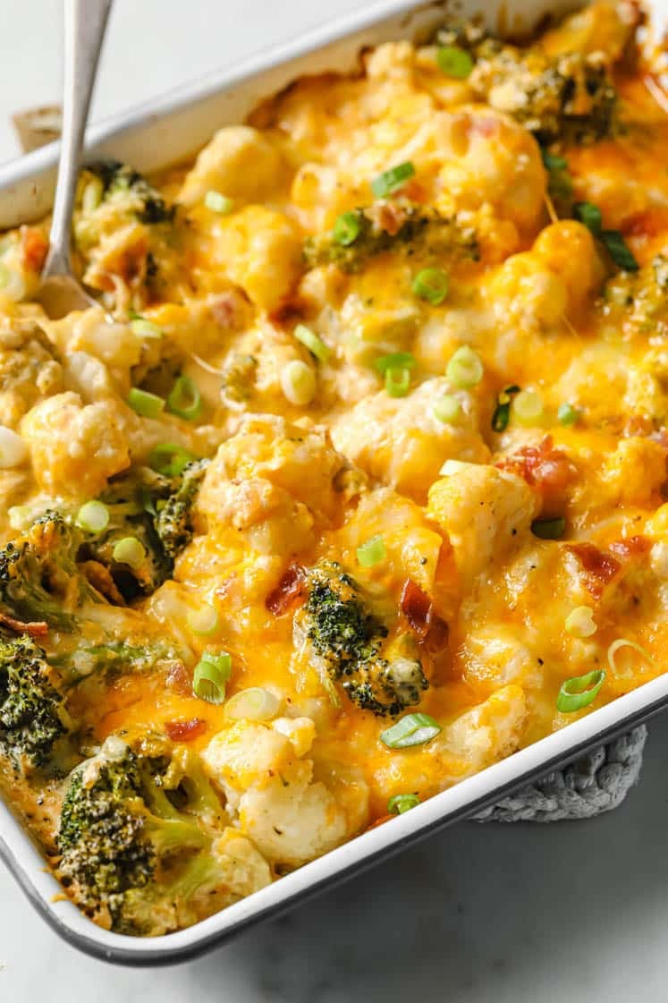 Loaded Broccoli Cauliflower Casserole on a baking dish with a fork atop a marble countertop.