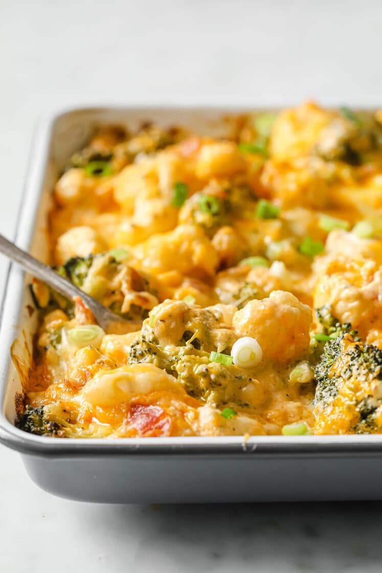 Loaded Broccoli Cauliflower Casserole on a baking dish with a fork atop a marble countertop.