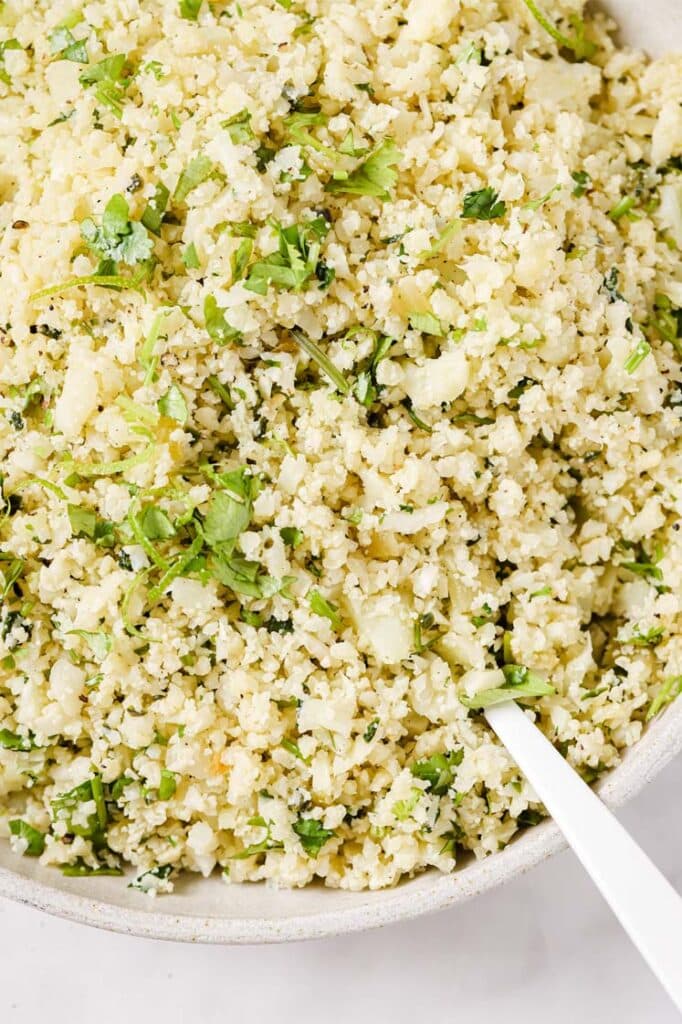 A bowl of cilantro lime cauliflower rice with a spoon.