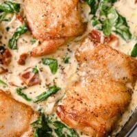 Close-up of creamy Tuscan chicken in an iron skillet.
