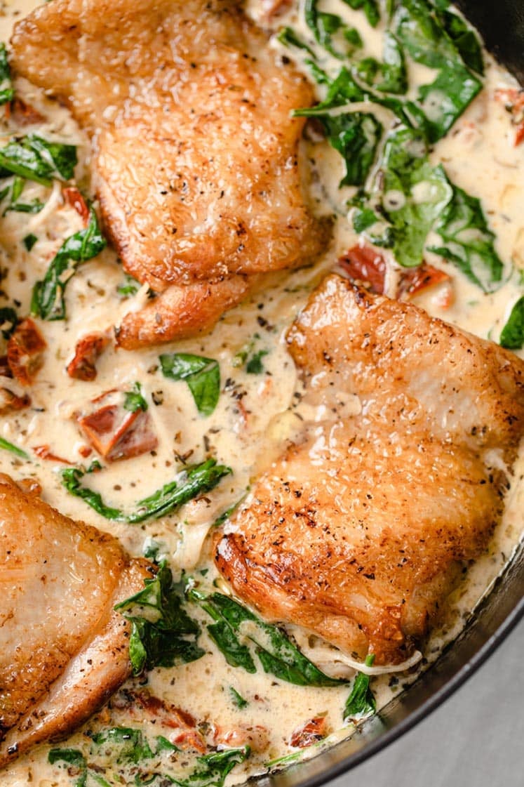 Close-up of creamy Tuscan chicken in an iron skillet.