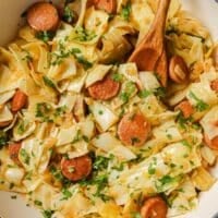 Cabbage and sausage on a pan with a wooden spoon.