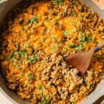 Creamy ground beef skillet with cauliflower rice on a cast iron skillet with a wooden spoon.