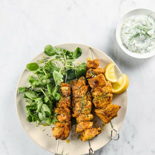 Shawarma kebabs, salad, and lemon on a plate with tzatziki on the side.