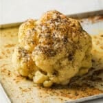 Buttery whole roasted cauliflower on a baking sheet.