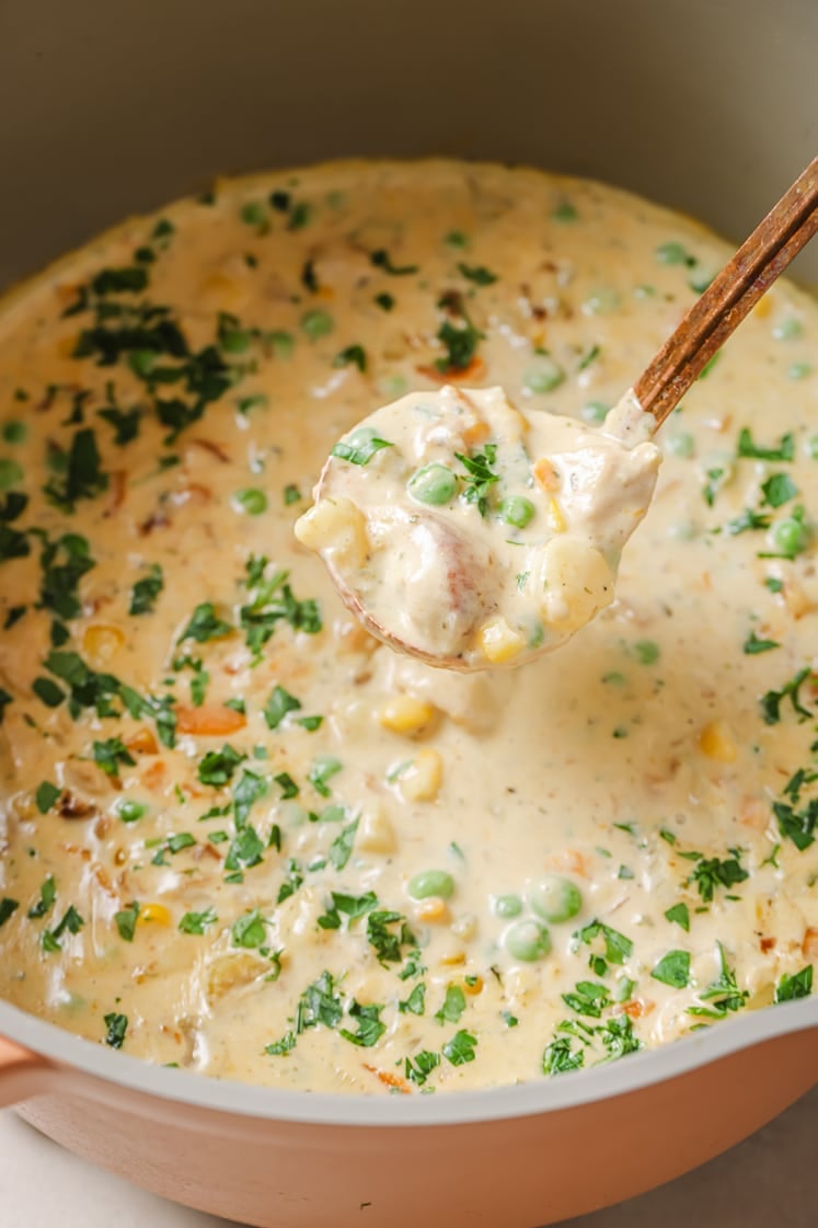 A pot of chicken pot pie soup with a portion on a ladle.