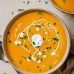 A bowl of garnished sweet potato and red pepper soup.