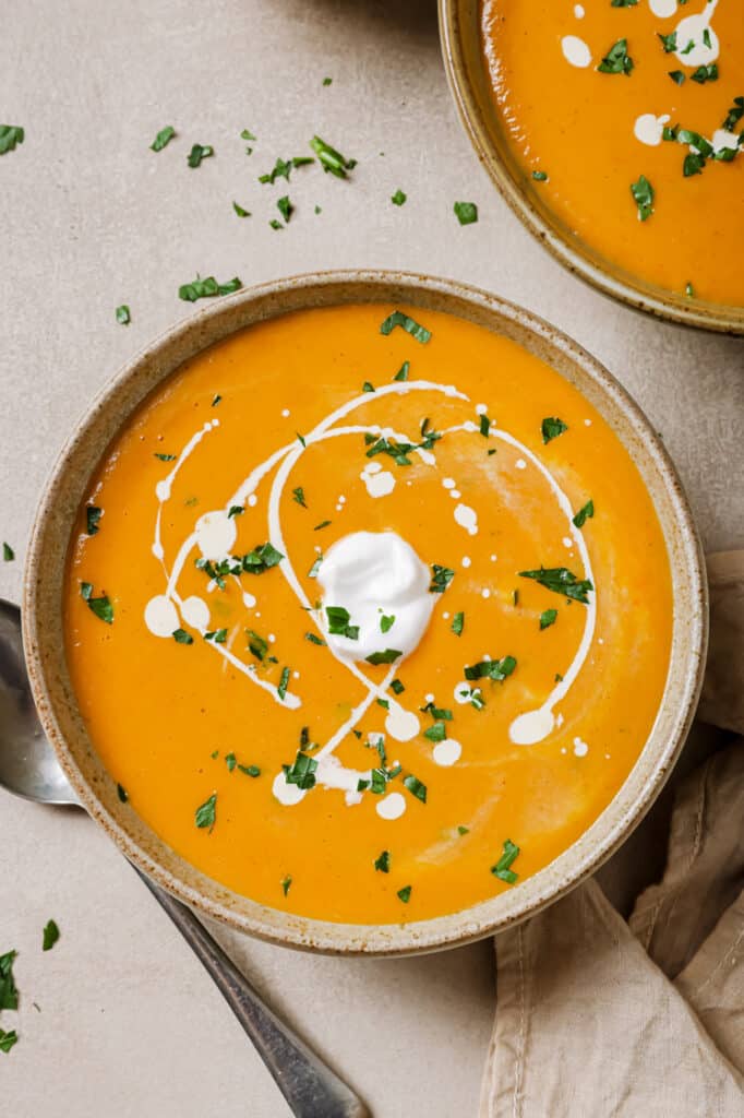 A bowl of garnished sweet potato and red pepper soup.